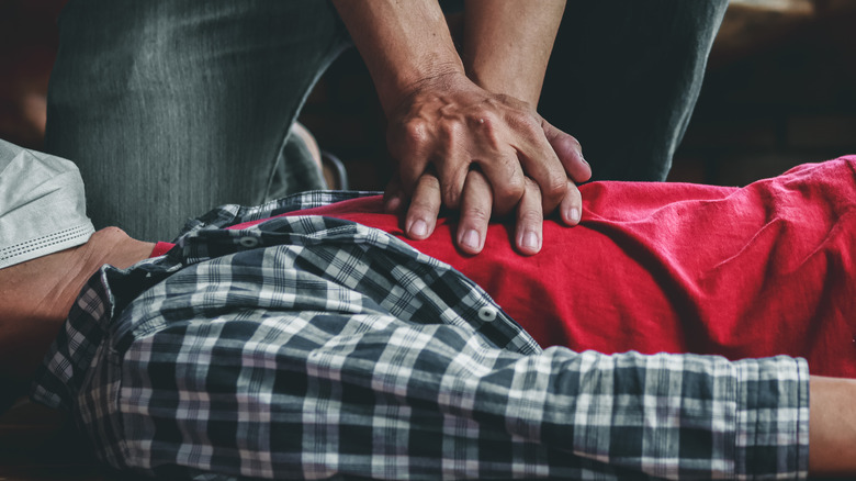 man's hands giving CPR to a man's chest