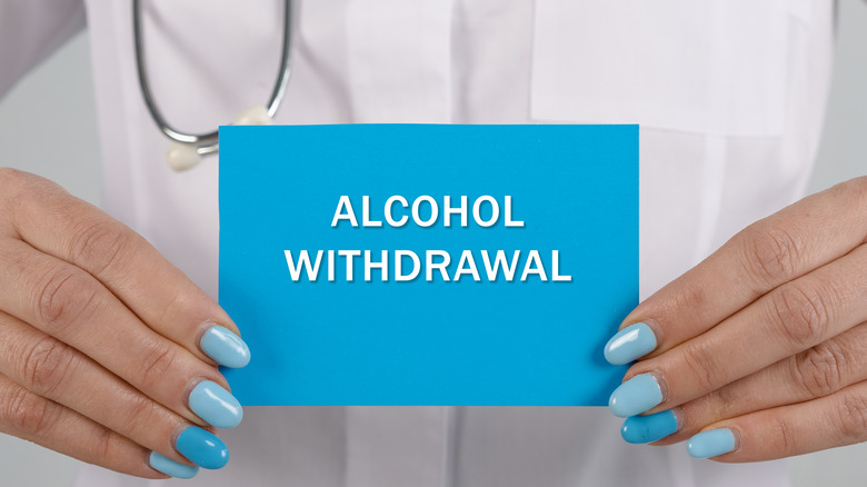 Female nurse holding blue alcohol withdrawal sign