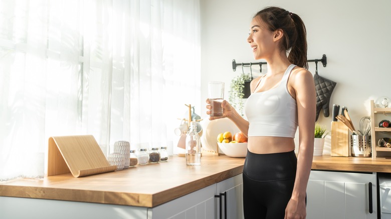 Woman drinking water in her kitchen