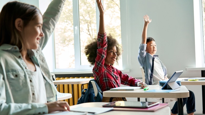 Children raising hands in classroom