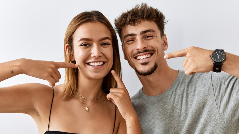 happy couple pointing to their clean teeth