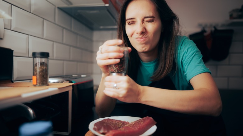 woman putting spices on meat