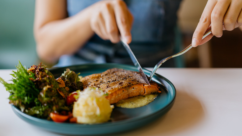 Hands cutting up salmon filet