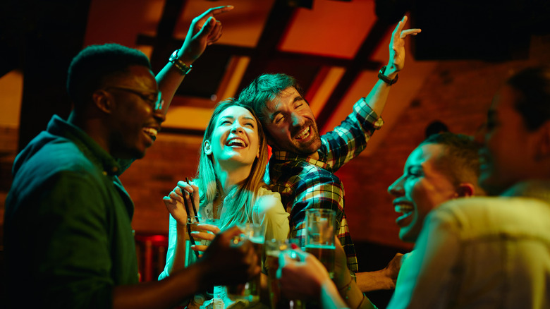 Smiling friends dancing at bar