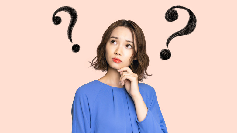 Woman thinking with hand on chin with question marks near her head