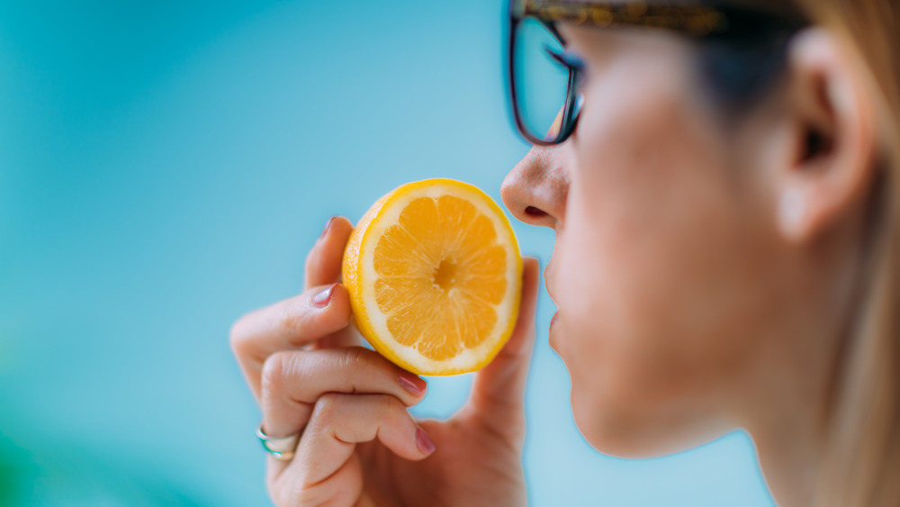 Woman sniffs half an orange