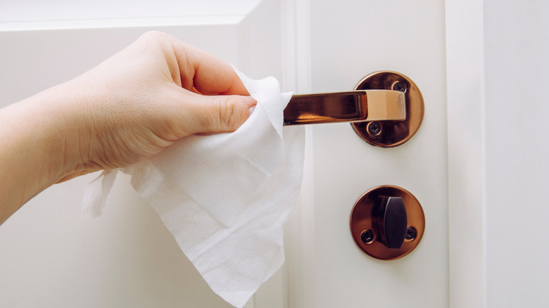Disinfecting door knob at house with wipe