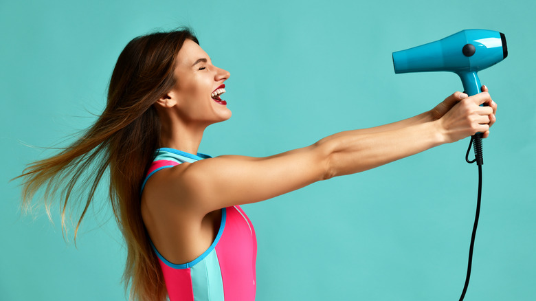 woman pointing blow dryer at face 