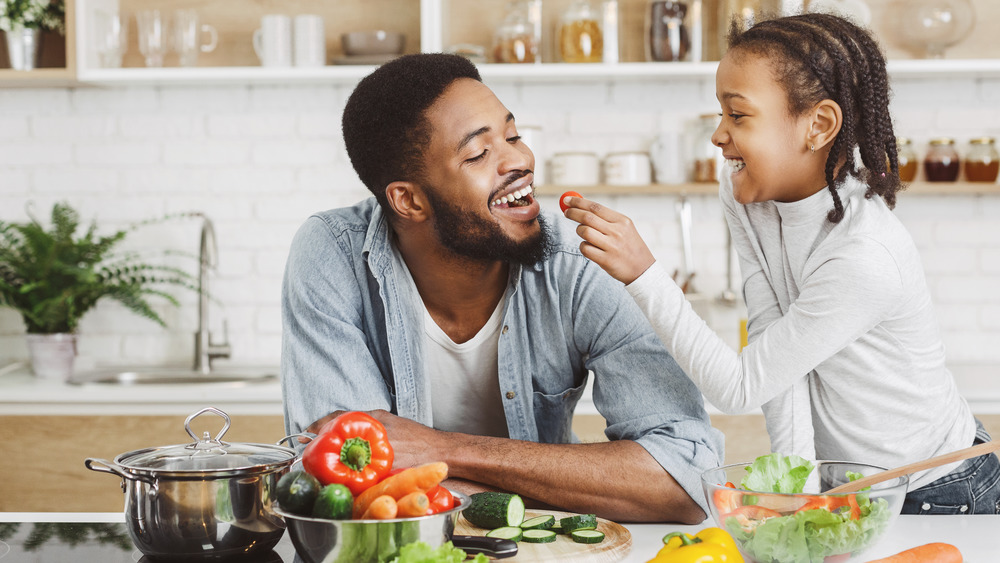 girl feeding her dad veggies