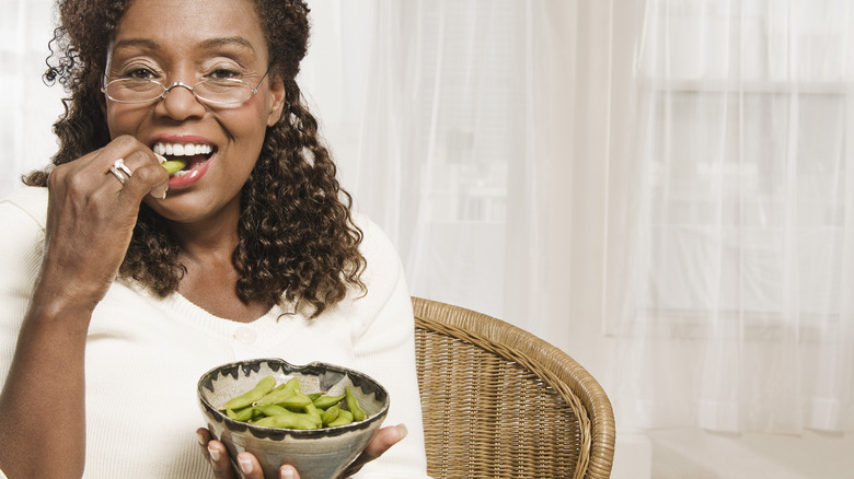 woman eating edamame in a bowl