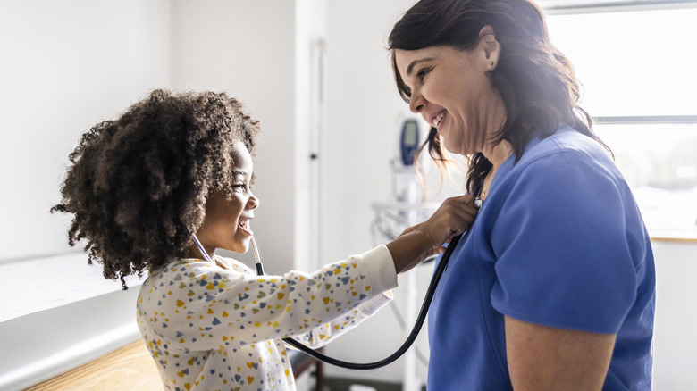 A young girl listening to a nurse's heart with a stethescope