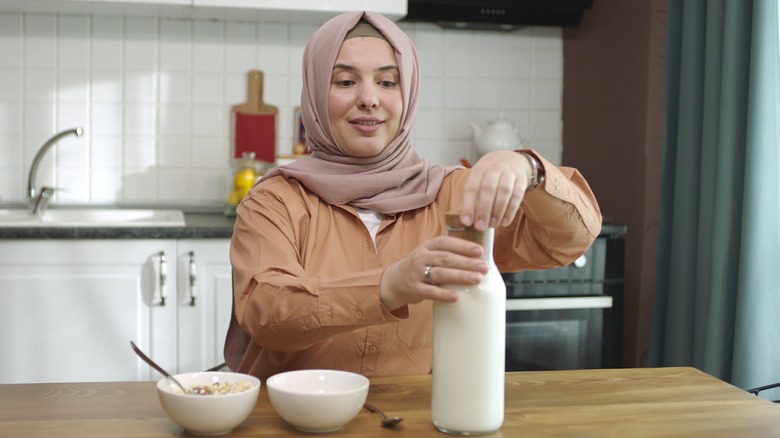 Woman opening glass bottle of milk