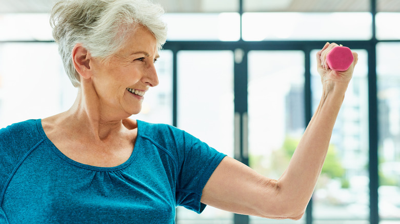 Old woman doing arm curl exercise with low body weight