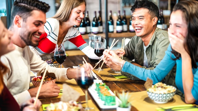 young people eating Japanese food at restaurant table