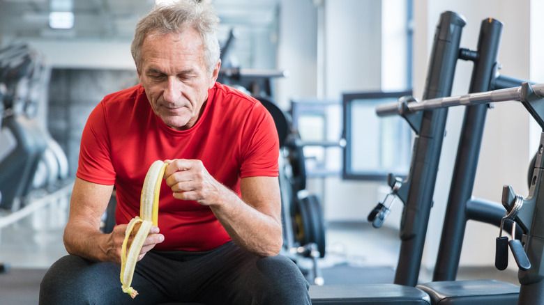 older man peeling a banana while at the gym