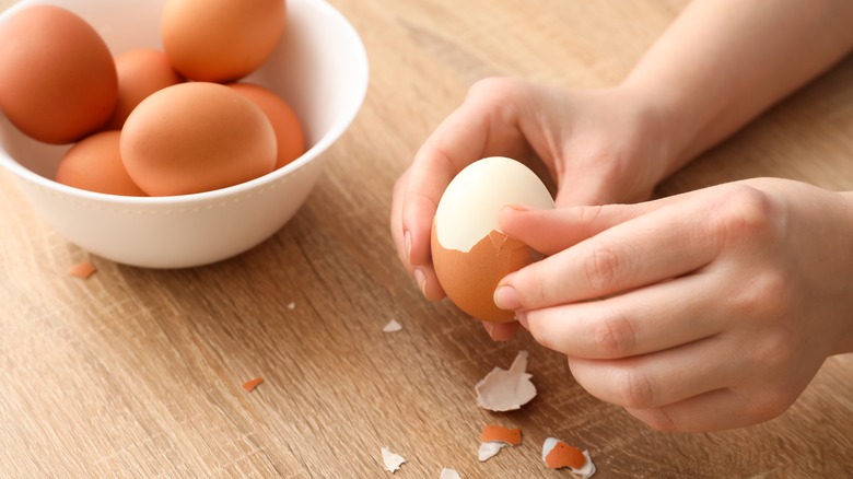 hands peeling hard boiled eggs