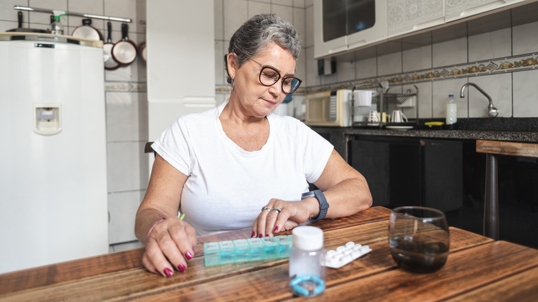 woman checking watch with medications on table