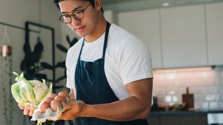 man holding cauliflower and eggs