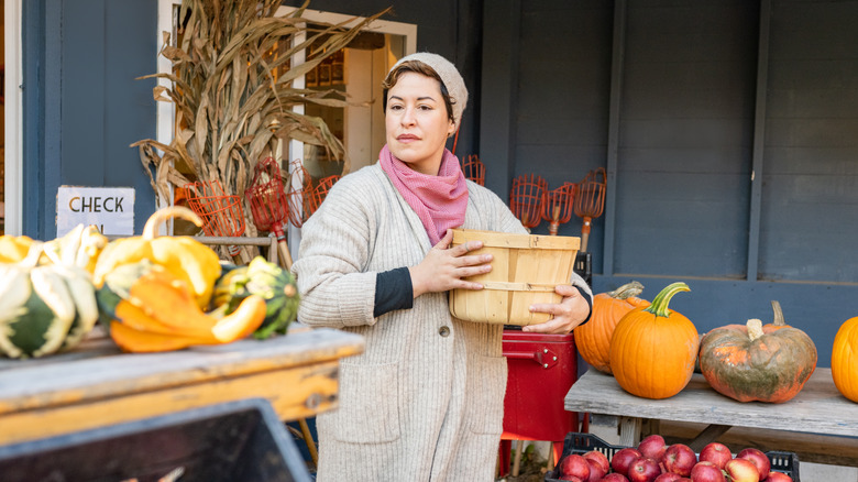 A woman deciding which squash to buy at the market