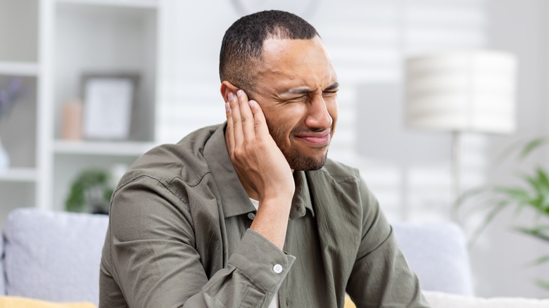 man with ear injury grimacing in pain