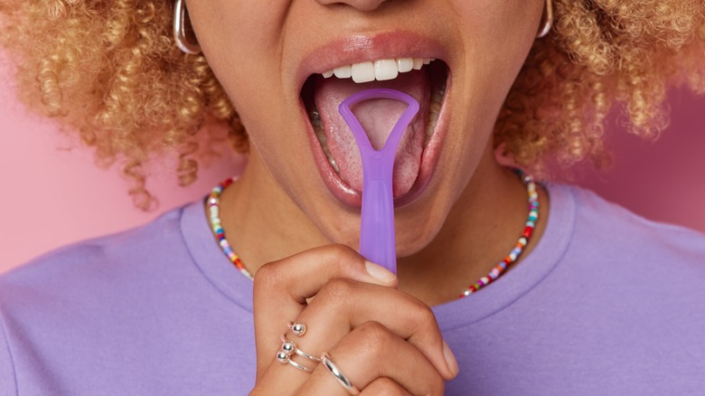 Woman using tongue scraper