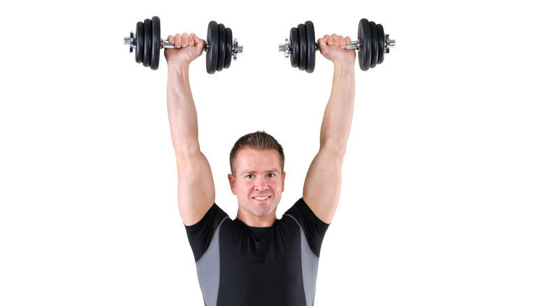 muscular man holding dumbbells over his head