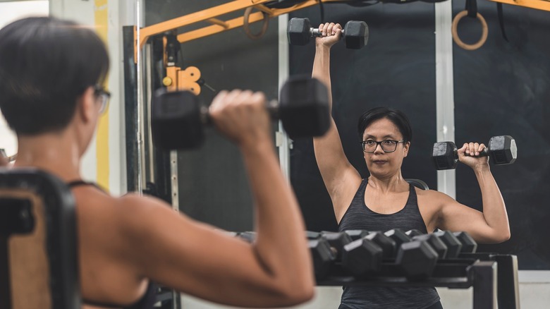 older woman doing single arm shoulder press