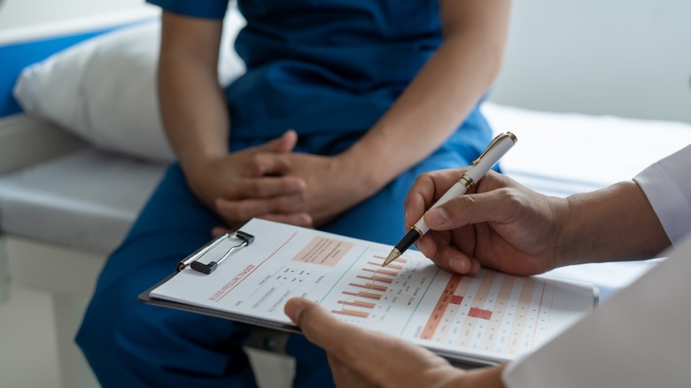 doctor writing on clipboard