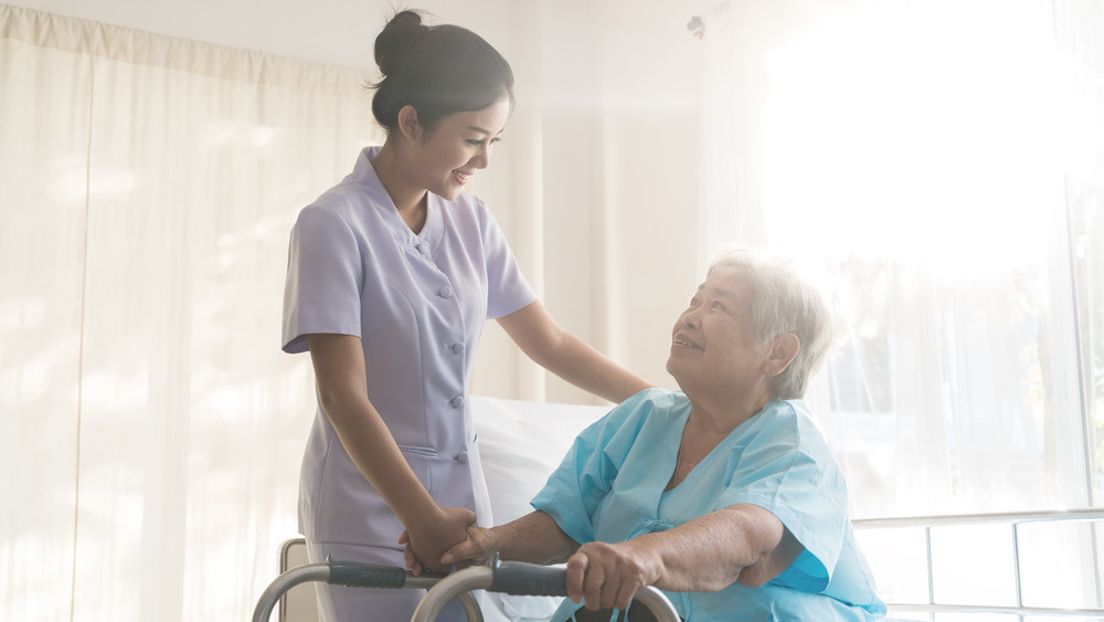 Nurse standing over a patient in a wheelchair and smiling