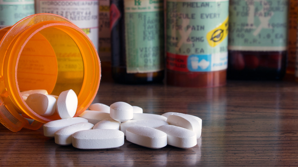 Orange pill bottle with pills spilling out on a table