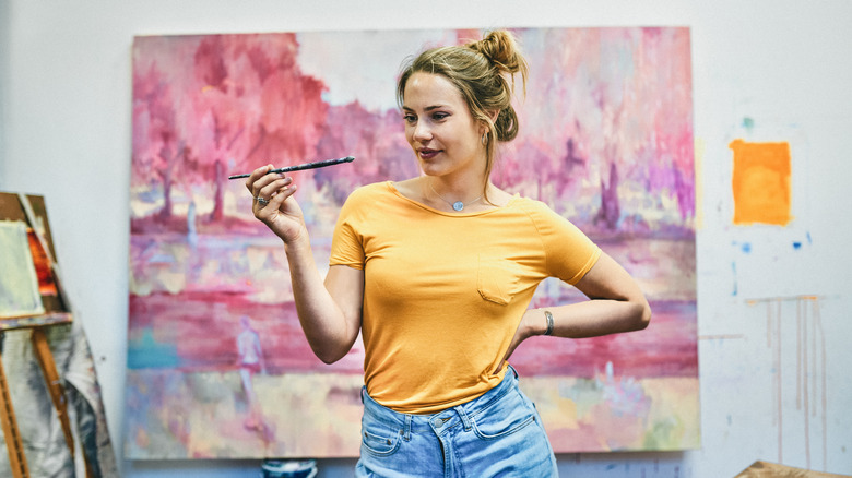 Young artist standing in front of painting
