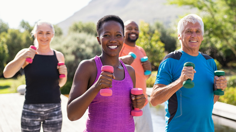 Group of men and women running outside while holding weights