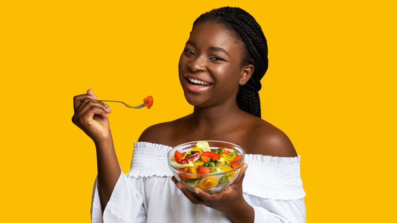 Black woman smiling eating salad