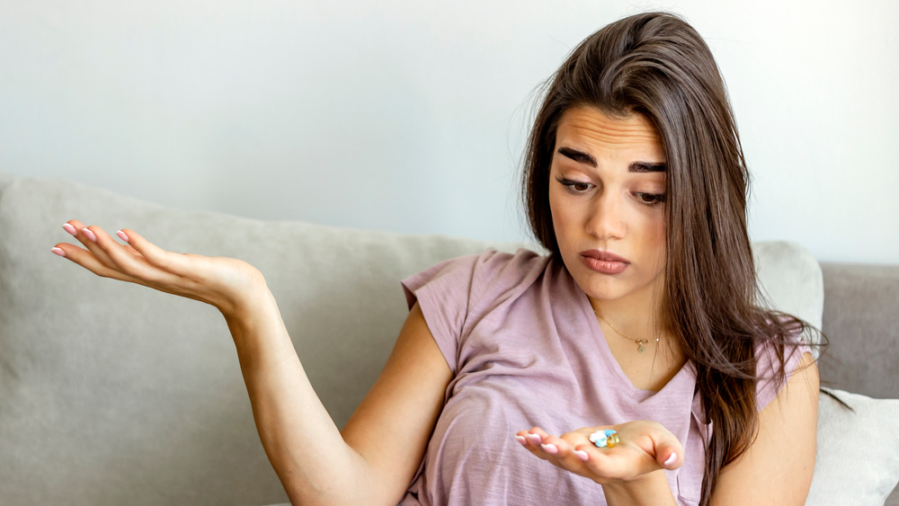 woman looking at pills in her hand