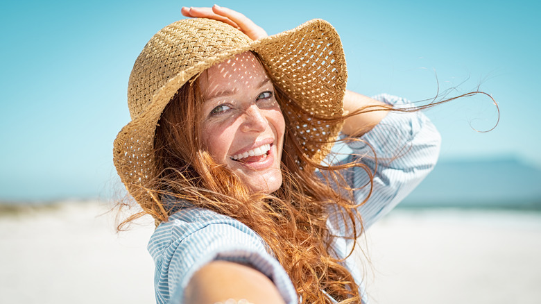 Woman smiling wearing straw hat at the beach