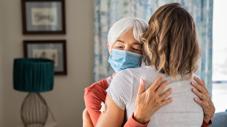 Two people hugging, one in a face mask