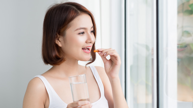 Woman taking vitamins near a window