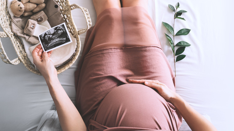 Pregnant woman holding belly and picture