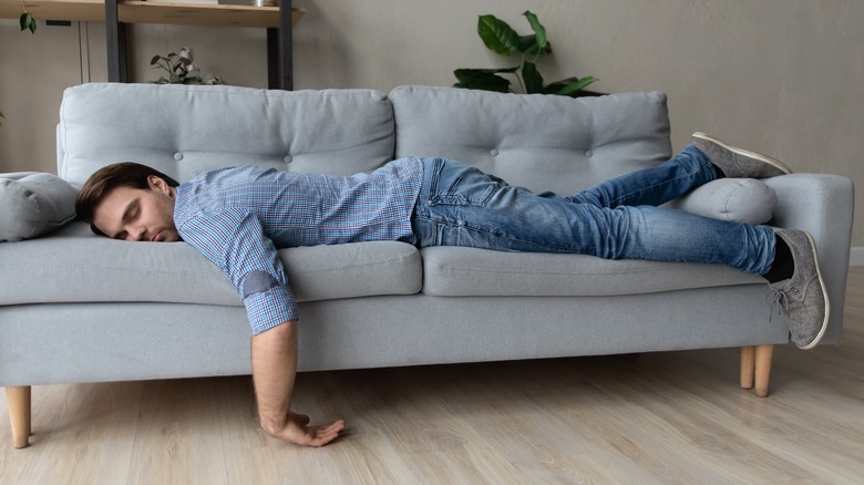Man asleep on couch face down