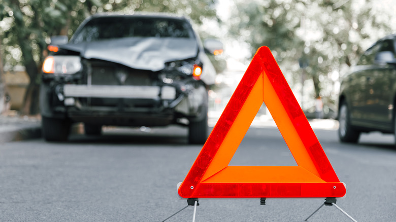 Dented car with warning sign in front