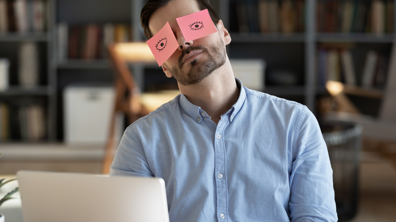 Sleepy man with post-it over eyes