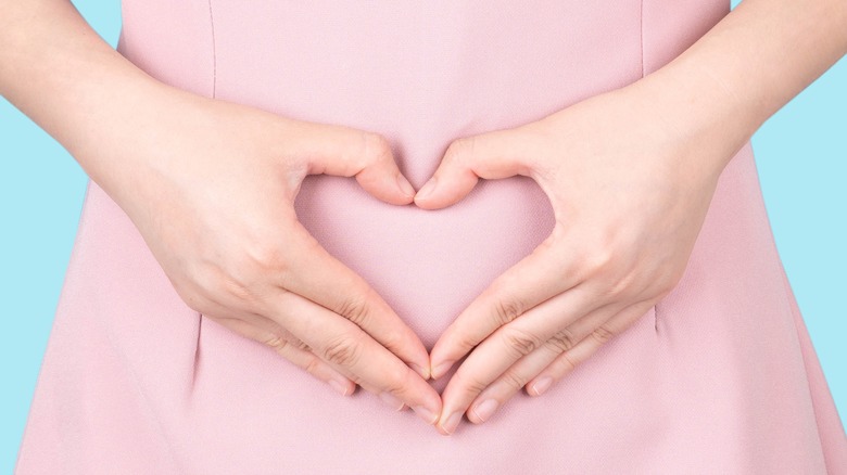 woman heart-shaped hands on gut