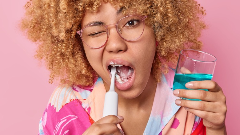 woman using mouthwash and brushing teeth