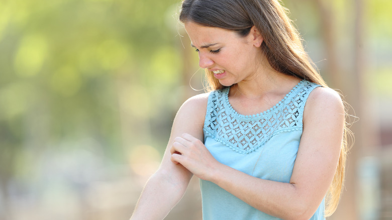 woman outside scratching itchy arm