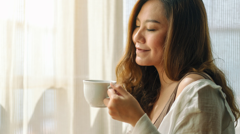 woman drinking coffee by window