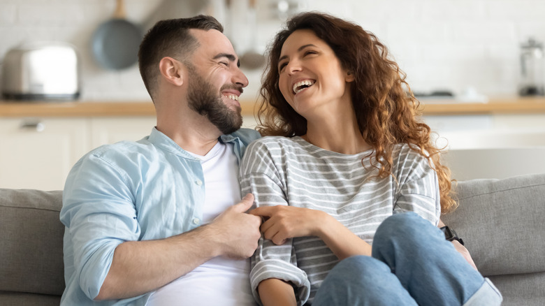 Man and woman laughing on couch