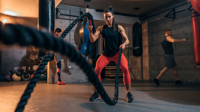 A woman uses heavy ropes at the gym