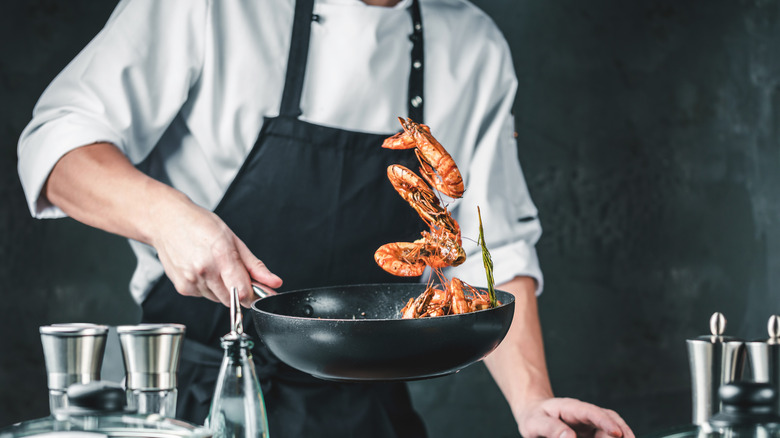 Chef is tossing shrimp in a pan