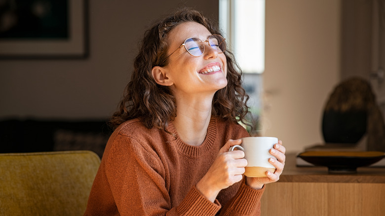 Woman holding mug smiling broadly