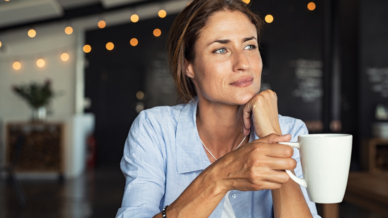 Woman holding mug off coffee at cafe